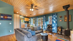 A cozy living room with a sofa, ottoman, and a glass coffee table. - Sunflower Cabin- Mountain Views- Hot tub (Florissant)