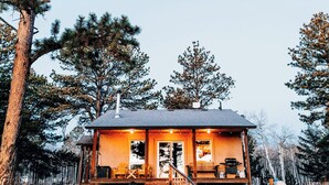 A rustic cabin with a stone foundation, wooden exterior, and a porch with outdoor seating. - Sunflower Cabin- Mountain Views- Hot tub (Florissant)