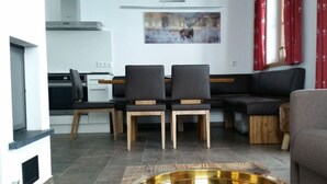 A modern living room with a dining area, a kitchen in the background, and a painting on the wall. - Alpin Residenzen Top 12 (Hollersbach im Pinzgau)