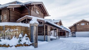 A wooden building with a sign reading "Alpin Residenzen" in a snowy setting. - Alpin Residenzen Top 12 (Hollersbach im Pinzgau)