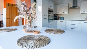 Una cocina moderna con armarios blancos, horno empotrado y campana extractora de acero inoxidable.