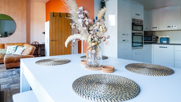 Una cocina moderna con armarios blancos, horno empotrado y microondas.