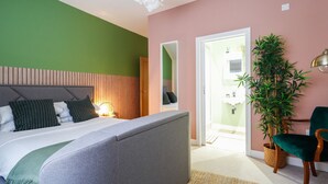 Un dormitorio con cama, mesita de noche, lámpara y una planta en maceta.