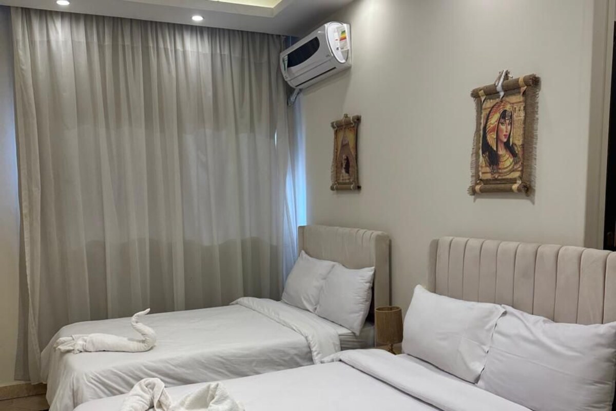 Une chambre d’hôtel avec deux lits, un ventilateur de plafond, un appareil de climatisation et une grande fenêtre avec des rideaux.