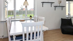 A dining area with a white table and chairs, a hanging pendant light, and a view of the outside. - 6 Person Holiday Home in Hadsund (Hadsund)