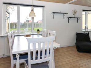 A dining area with a white table and chairs, a hanging pendant light, and a view of the outside. - 6 Person Holiday Home in Hadsund (Hadsund)
