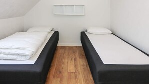 A small, single-room accommodation with two beds, a wooden floor, and a sloped ceiling. - 6 Person Holiday Home in Hadsund (Hadsund)