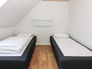A small, single-room accommodation with two beds, a wooden floor, and a sloped ceiling. - 6 Person Holiday Home in Hadsund (Hadsund)