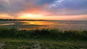 A coastal landscape with a sunset, grassy foreground, and a calm sea. - 6 Person Holiday Home in Hadsund (Hadsund)