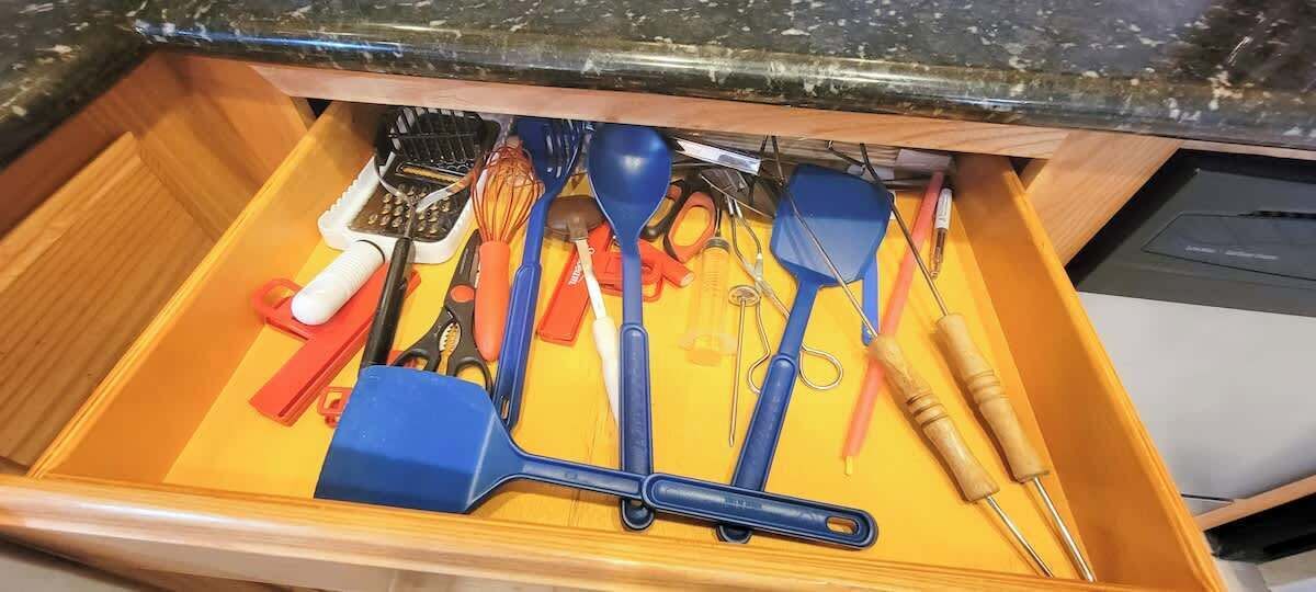 Un cajón con diversos utensilios de cocina, como espátulas, batidores y un par de tijeras.