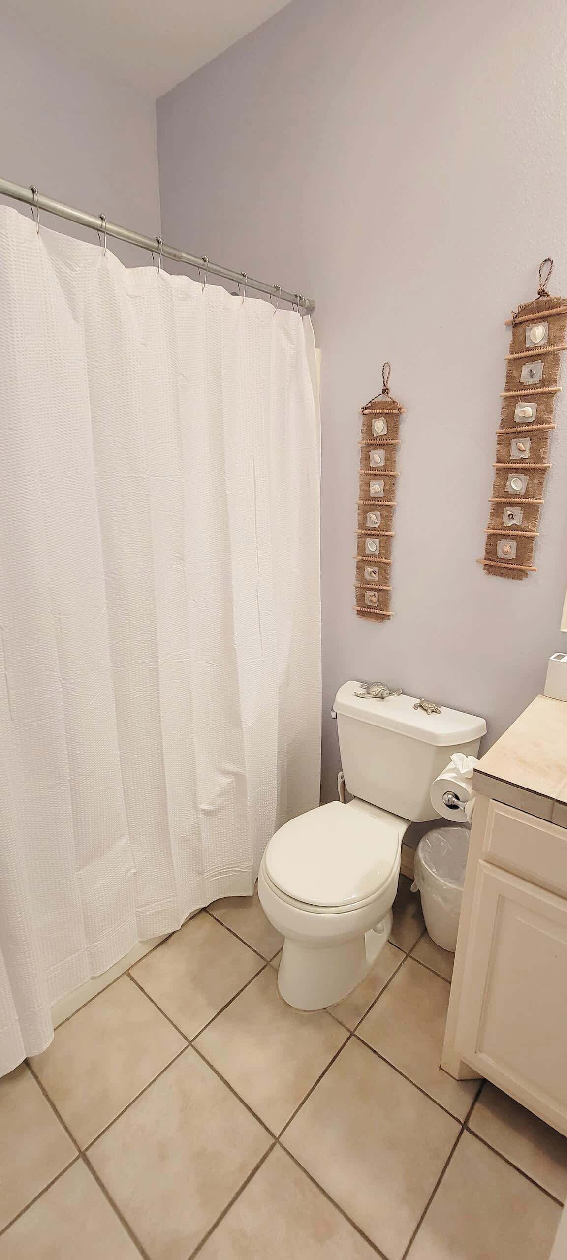 A bathroom with a white toilet, a shower curtain, and a sink with a mirror.