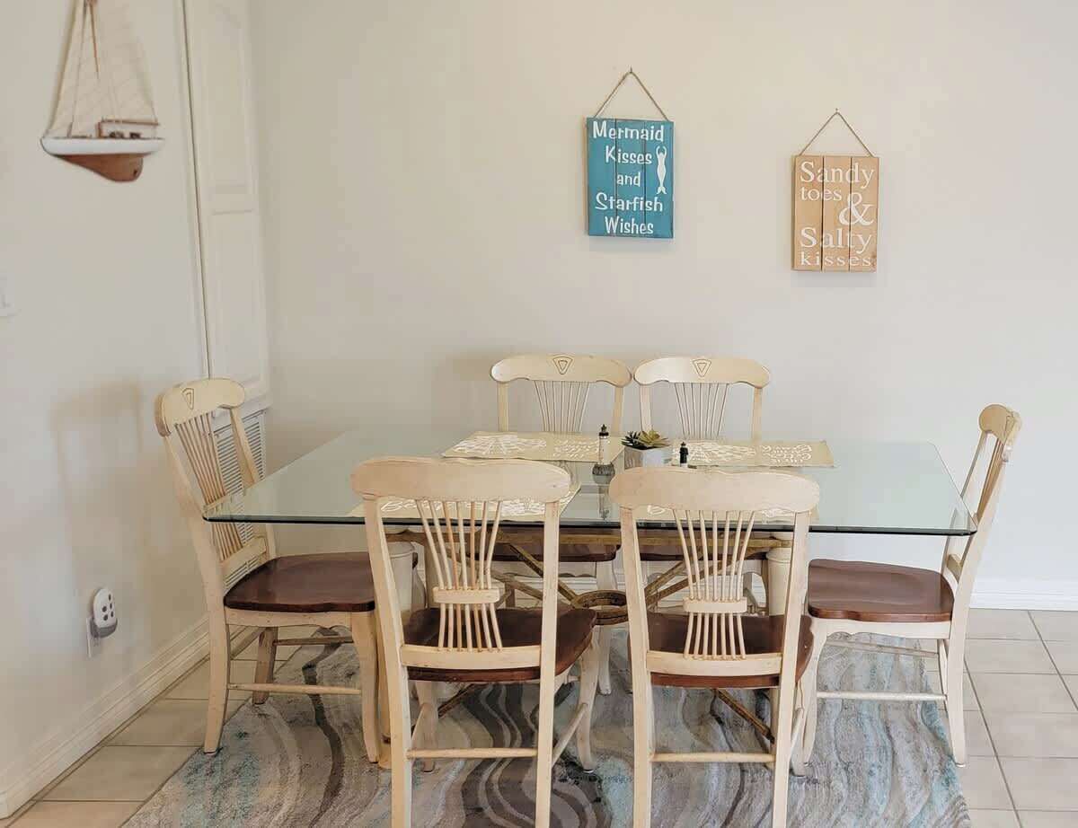 Un comedor con una mesa de vidrio rodeada de sillas de madera con asientos acolchados.
