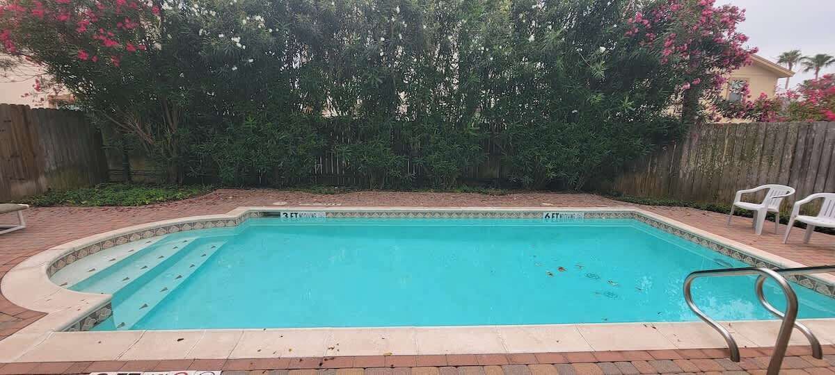 A rectangular swimming pool with a tiled edge and a metal ladder.