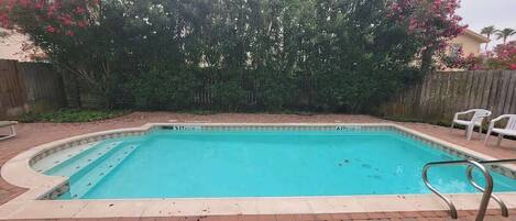 A rectangular swimming pool with a tiled edge and a metal ladder.