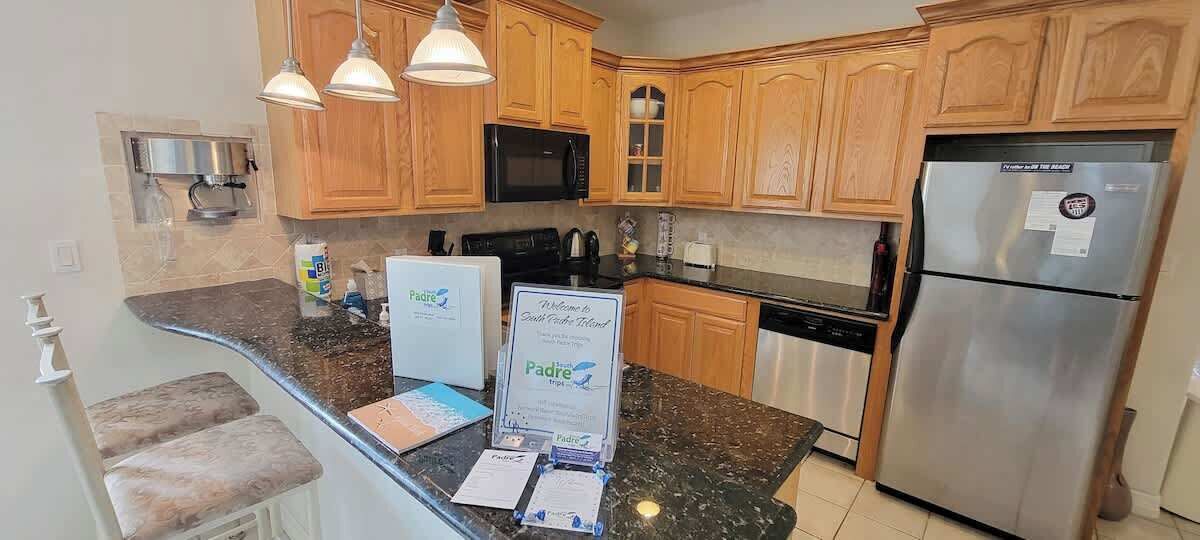 A kitchen with wooden cabinets, a stainless steel refrigerator, a microwave, and a coffee maker.
