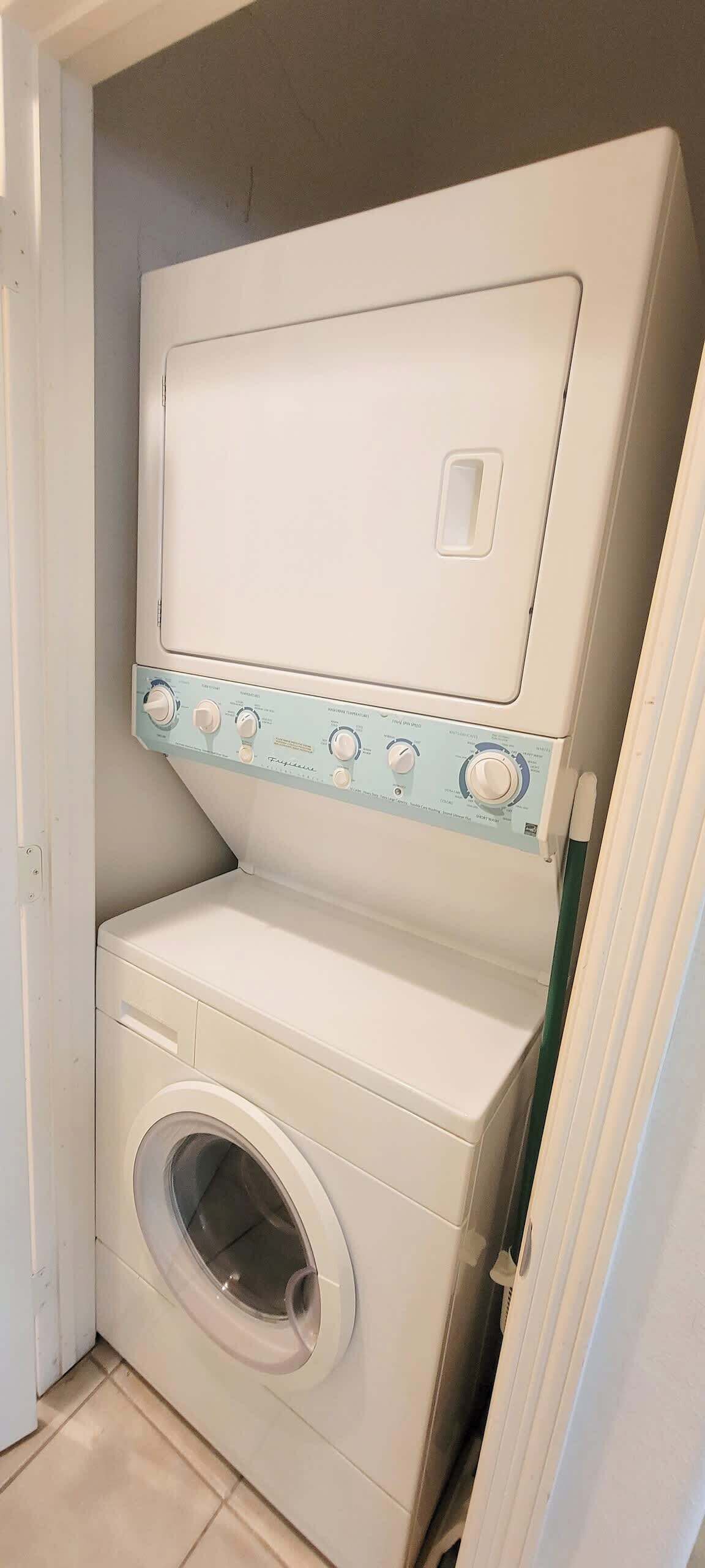 A compact, white front-loading washing machine with a control panel on top and a front door.