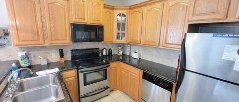 A kitchen with wooden cabinets, a stainless steel refrigerator, a microwave, an oven, a dishwasher, and a sink.