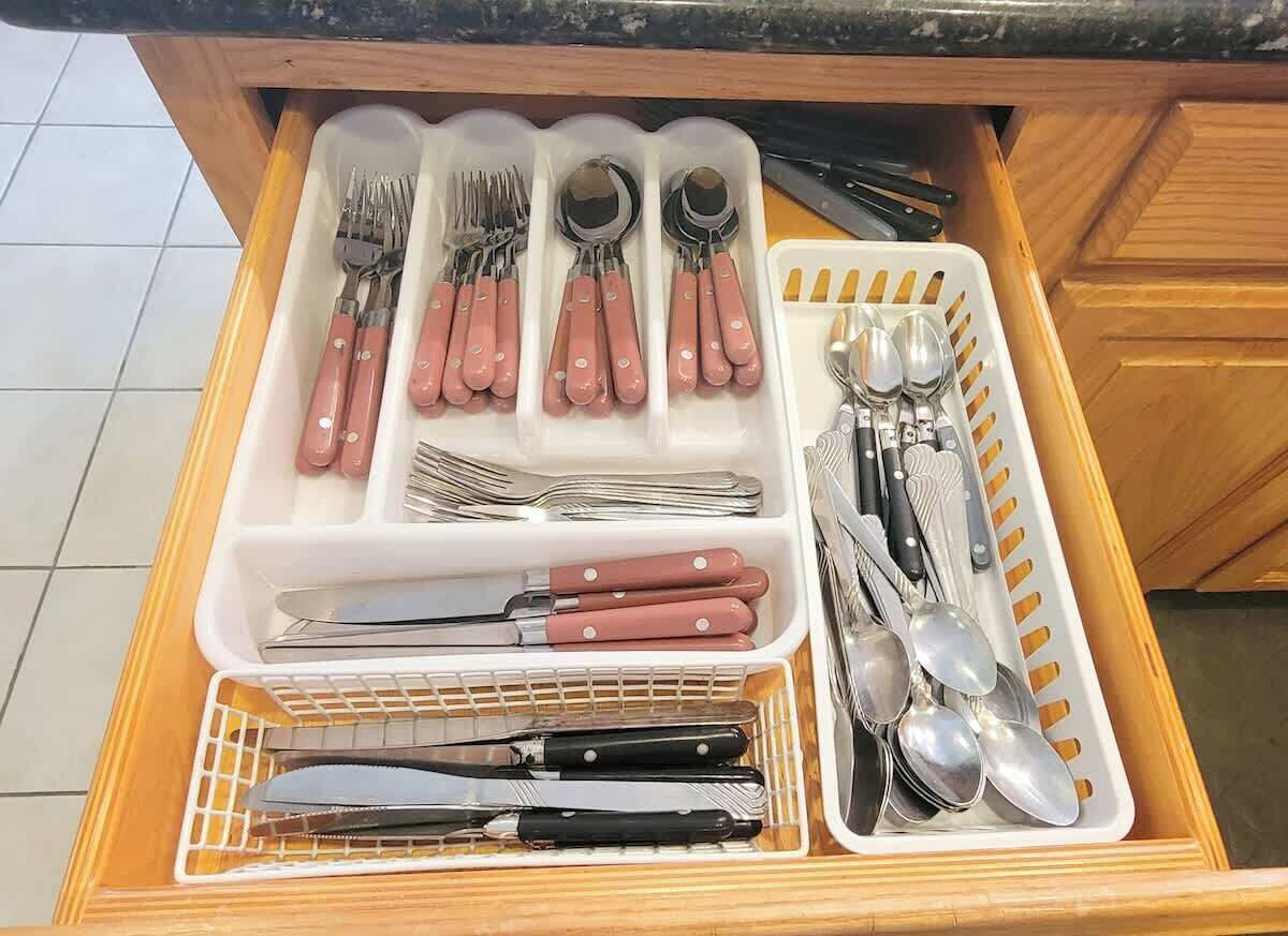 A kitchen drawer with utensils organized in compartments.
