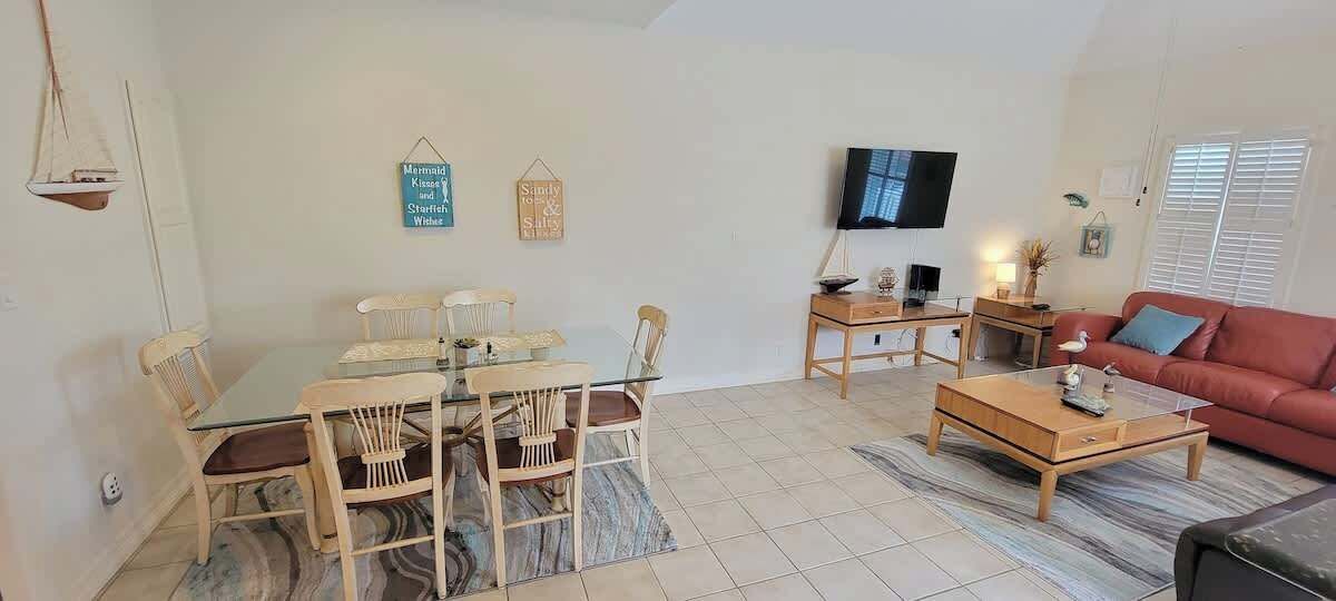 Ein Wohnzimmer mit Esstisch, Stühlen, einer Couch, einem Fernseher und einem Couchtisch.
