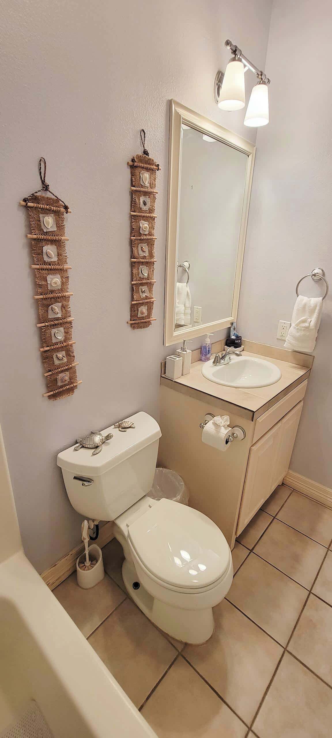 A bathroom with a white toilet, a sink with a mirror above it, and two wall-mounted light fixtures.