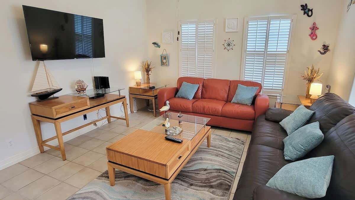A living room with a TV, two sofas, a coffee table, and a TV stand.