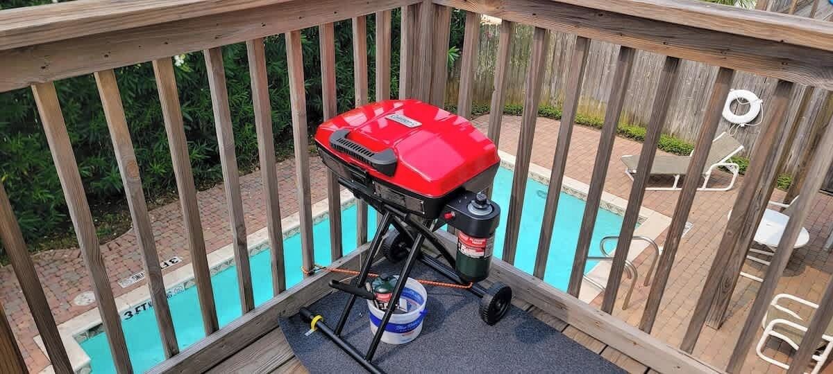 A barbecue grill on a deck overlooking a swimming pool.
