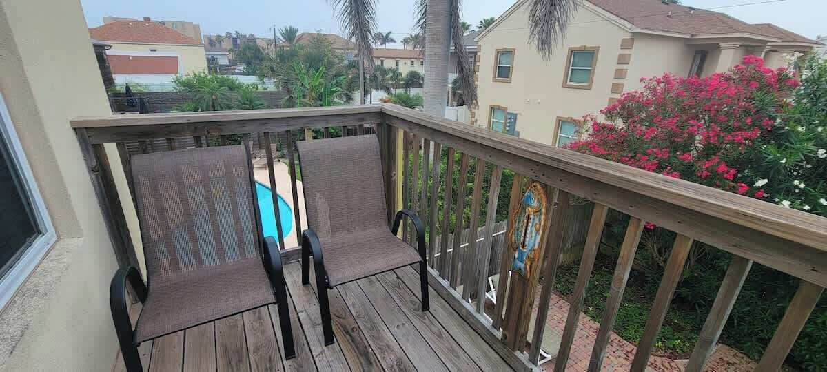 A wooden deck with two chairs and a pool in the background.