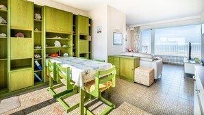 Ein Zimmer mit Esstisch, Stühlen, einer Küchenzeile und Meerblick.