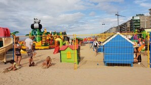 Ein Strandspielplatz mit Rutschen und Spielgeräten, umzäunt.