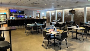 A restaurant with a bar area, tables, chairs, and a brick wall. - The Hudson Inn (Morris)