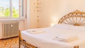 A bedroom with a bed, a radiator, a window, and a chandelier. - Tra Cielo e Terra - Italian Homing (Desenzano del Garda)