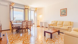 A living room with a sofa, a coffee table, and a dining area with a table and chairs. - Tra Cielo e Terra - Italian Homing (Desenzano del Garda)