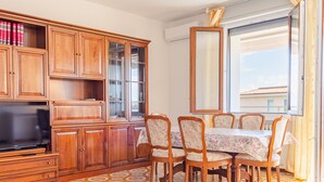 A living room with a TV, wooden cabinets, a dining table with chairs, and patterned floor tiles. - Tra Cielo e Terra - Italian Homing (Desenzano del Garda)