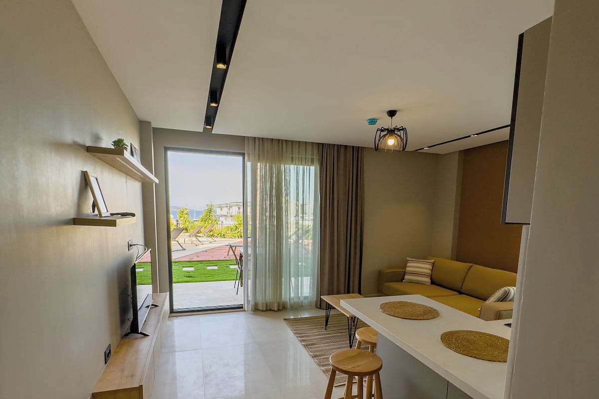 A modern kitchen with a dining area, a TV, and a view of the outdoors.