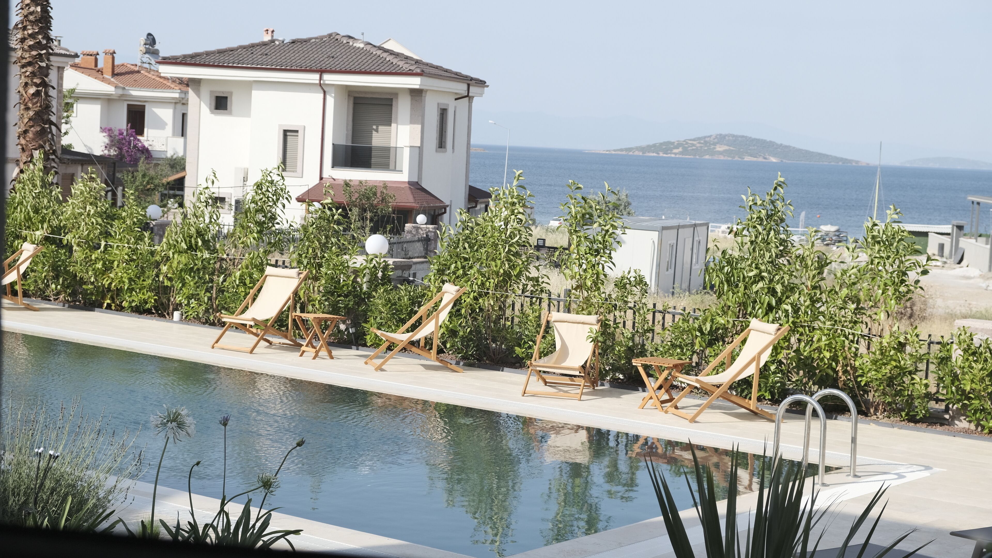 A pool area with lounge chairs and a view of the sea.