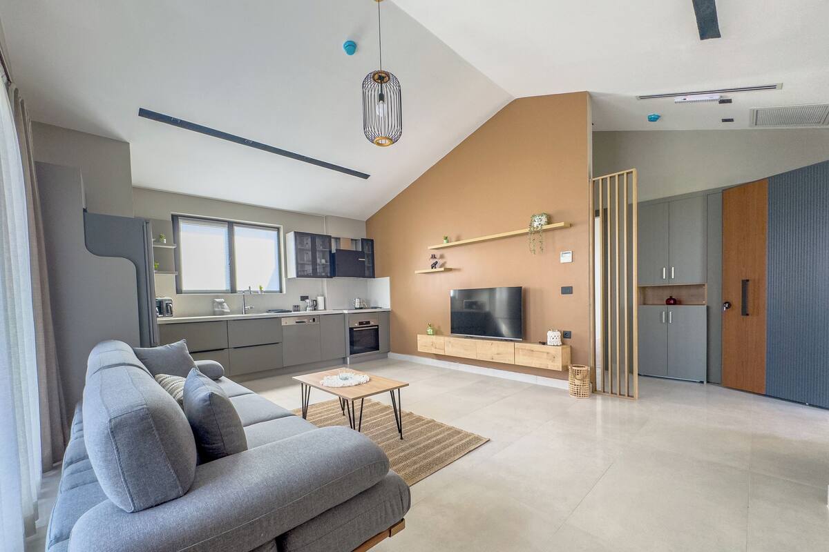 A modern living room with a grey sofa, a coffee table, and a TV.