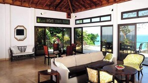 A spacious living area with a high ceiling, large windows, and a view of the ocean.