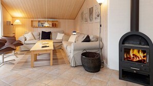 Een gezellige woonkamer met een open haard, houten plafond en een zithoek.
