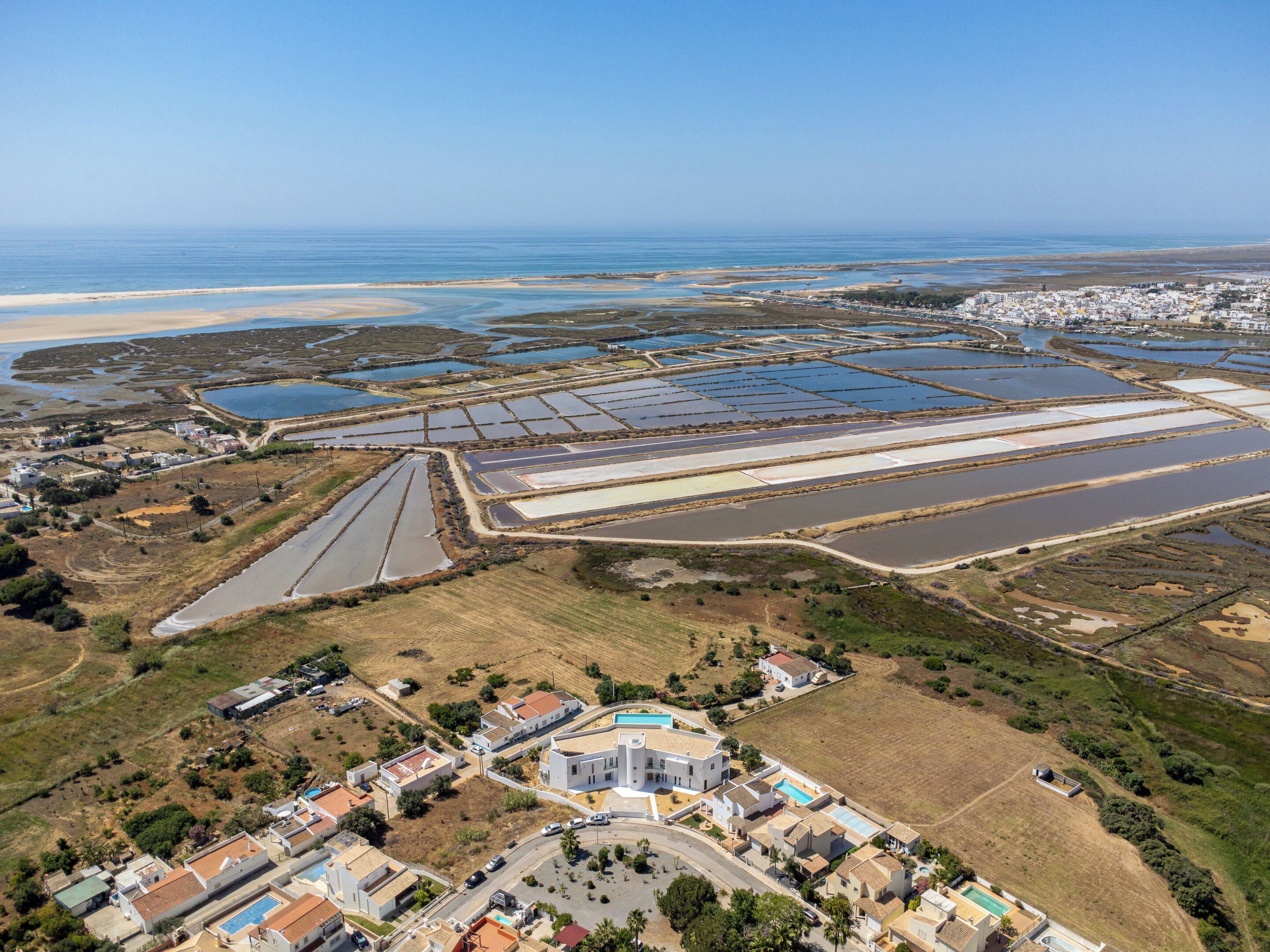 Vue aérienne d’une zone côtière avec des immeubles résidentiels, une piscine et un grand étang d’eau salée.