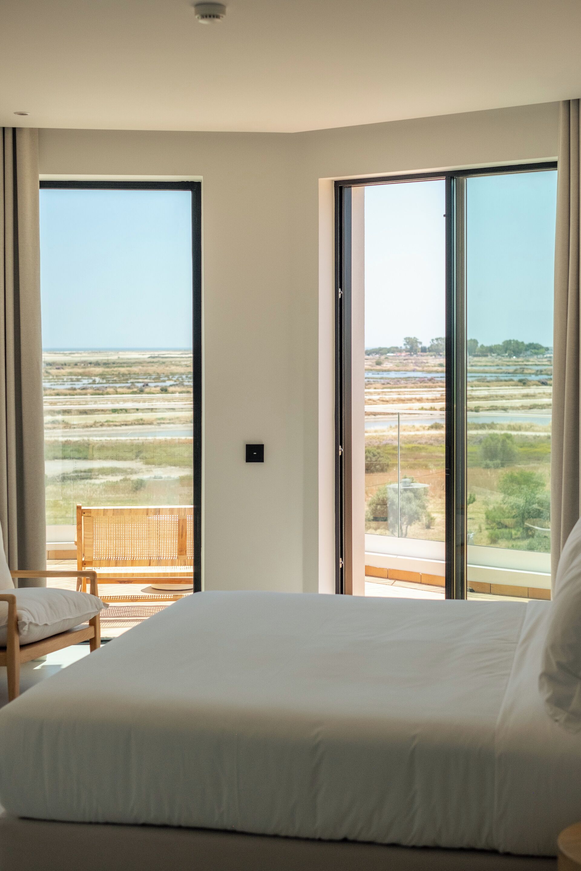 Un dormitorio con una cama grande, una silla y un balcón con vistas al paisaje.
