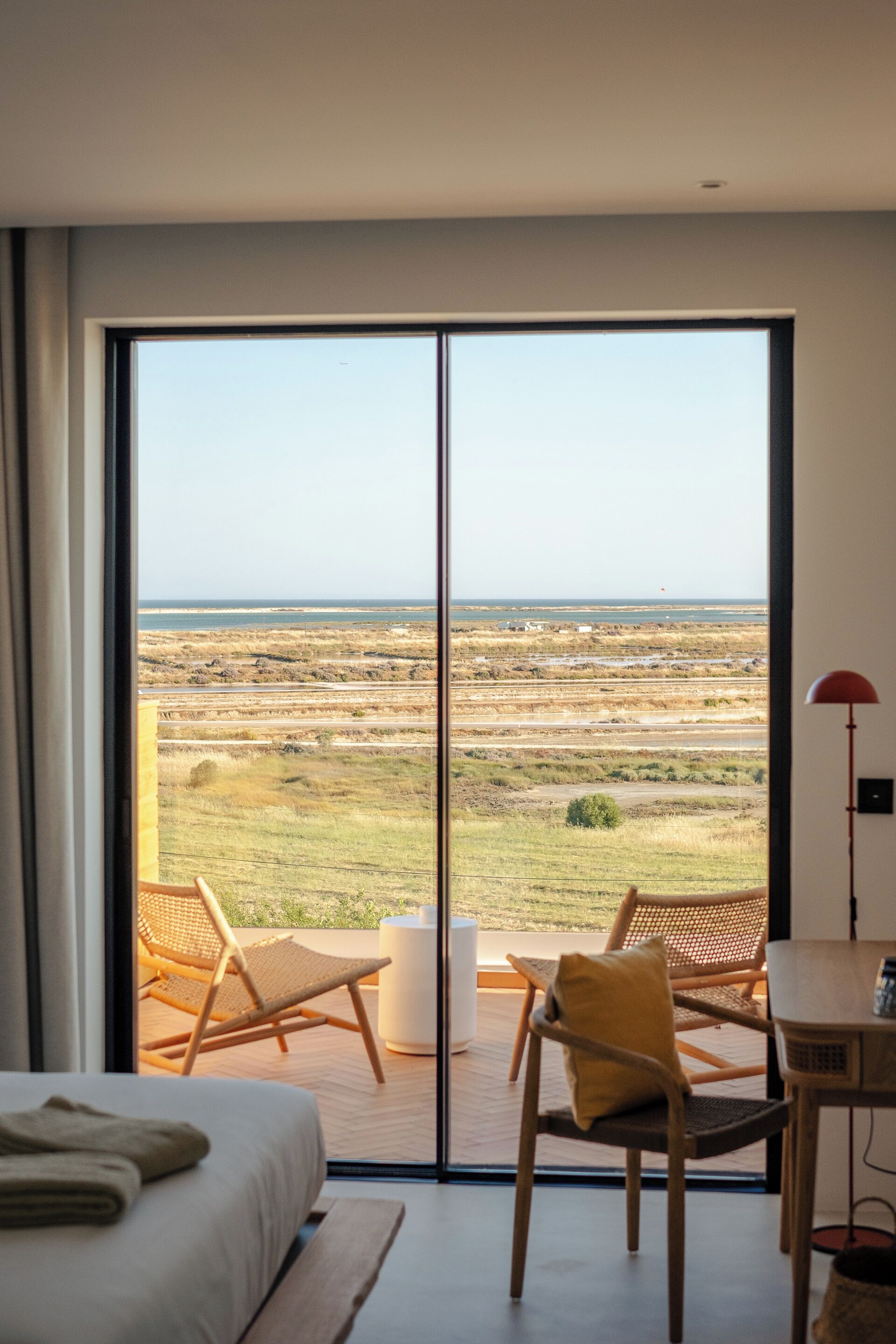 A bedroom with a large sliding glass door leading to an outdoor area with a view of the landscape.