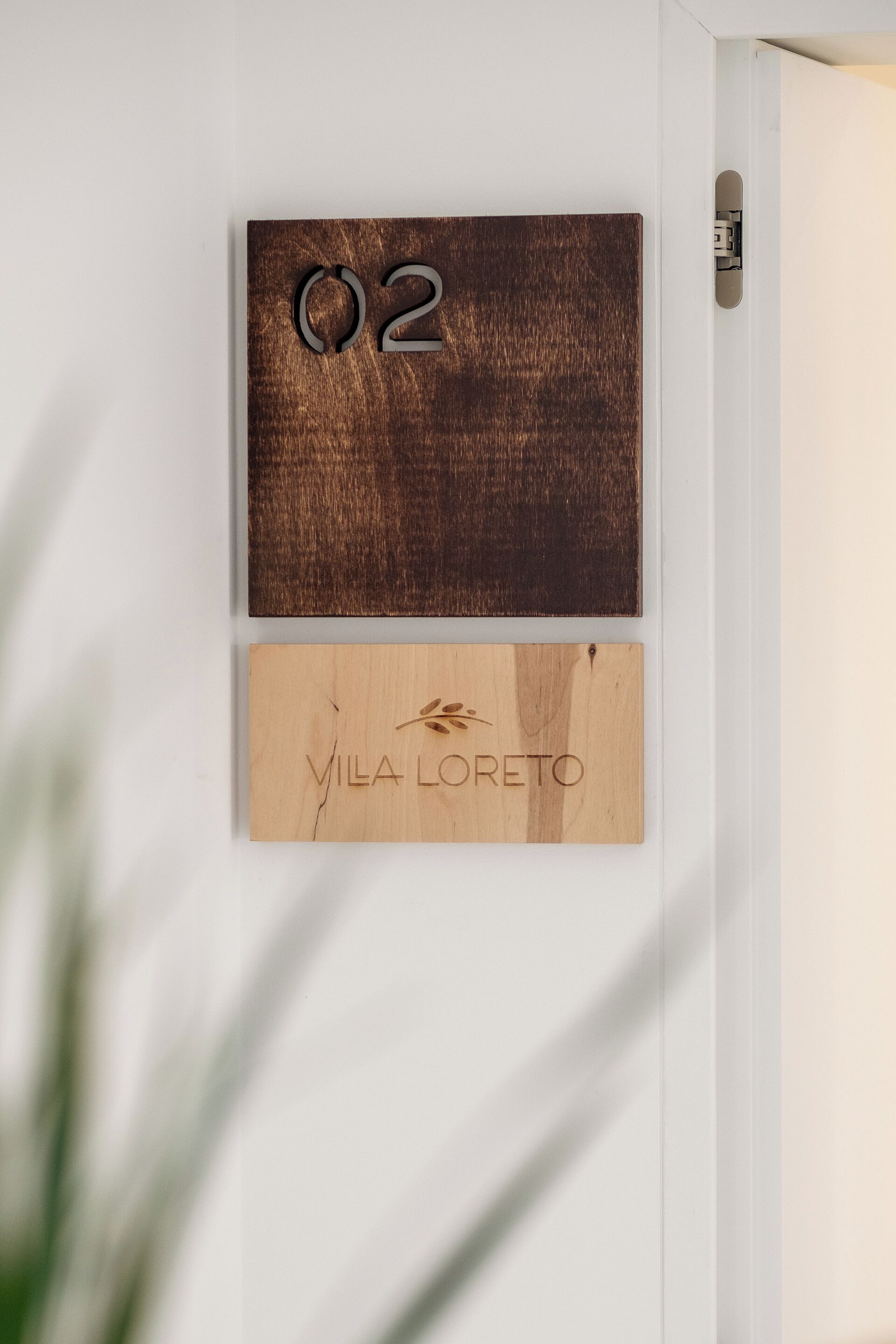 Una puerta de madera con el número '02' y una placa con el nombre 'VILA LORETO'.