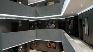 A multi-level interior with a modern design, featuring a central open space and artwork on the walls. - Qianxun Intelligent Hotel Haiyisu (Qibala International Resort) (Menghai)