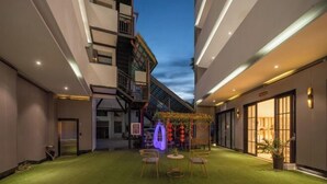 A hotel courtyard with a green lawn, outdoor seating, and a decorative arch. - Qianxun Intelligent Hotel Haiyisu (Qibala International Resort) (Menghai)