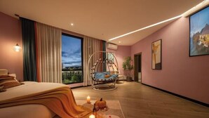 A modern bedroom with a bed, a hanging chair, a large window, and a view of the outdoors. - Qianxun Intelligent Hotel Haiyisu (Qibala International Resort) (Menghai)