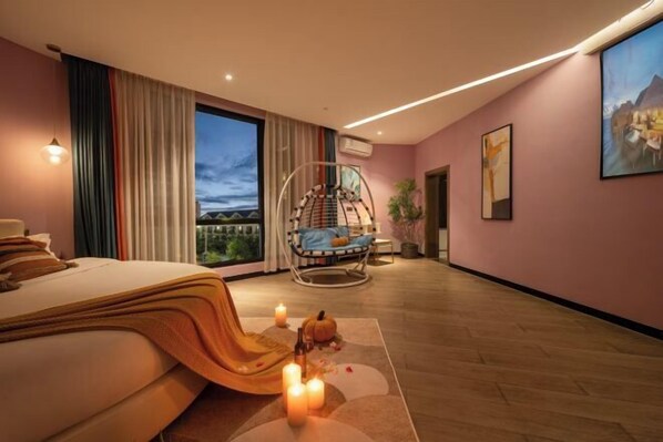 A modern bedroom with a bed, a hanging chair, a large window, and a view of the outdoors. - Qianxun Intelligent Hotel Haiyisu (Qibala International Resort) (Menghai)