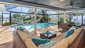 Un espacio exterior con piscina, mobiliario de mimbre y ventilador de techo.