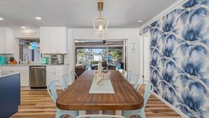 Una cocina moderna con armarios blancos, una mesa de comedor de madera y vistas al exterior.