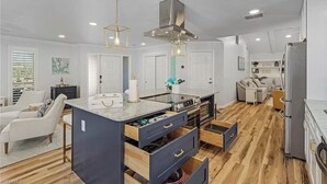 Una cocina moderna con una isla central, electrodomésticos integrados y un área de comedor con sofá y sillas.