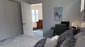 Un dormitorio con cama, escritorio, silla y mesita de noche con lámpara.